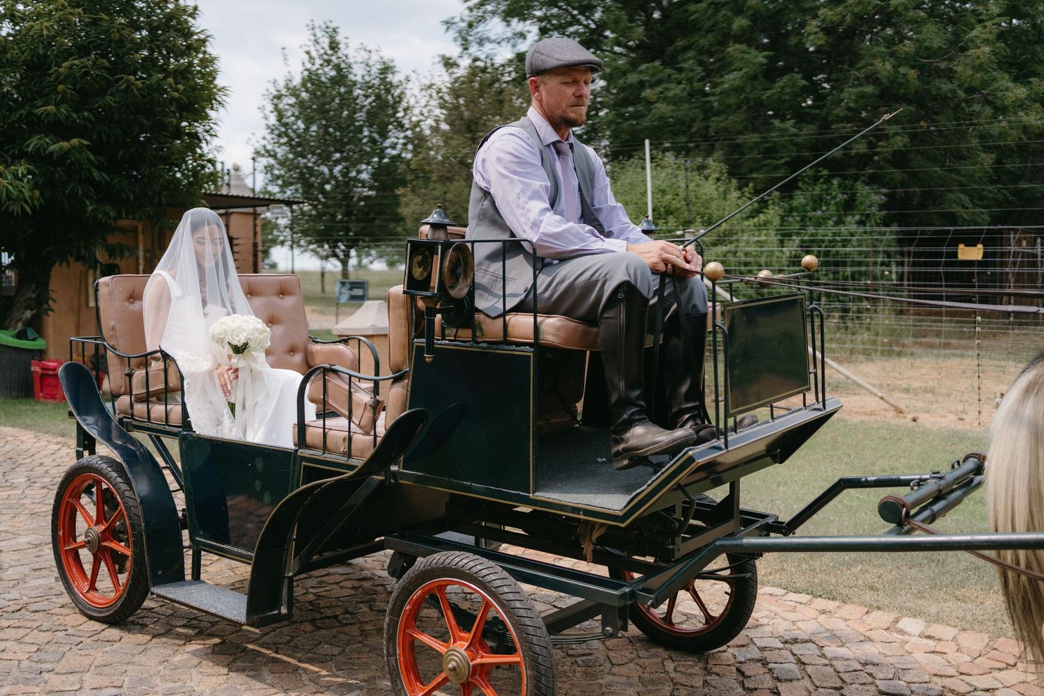 A vintage horse carriage decorated with wedding decor stands in a rustic outdoor setting.