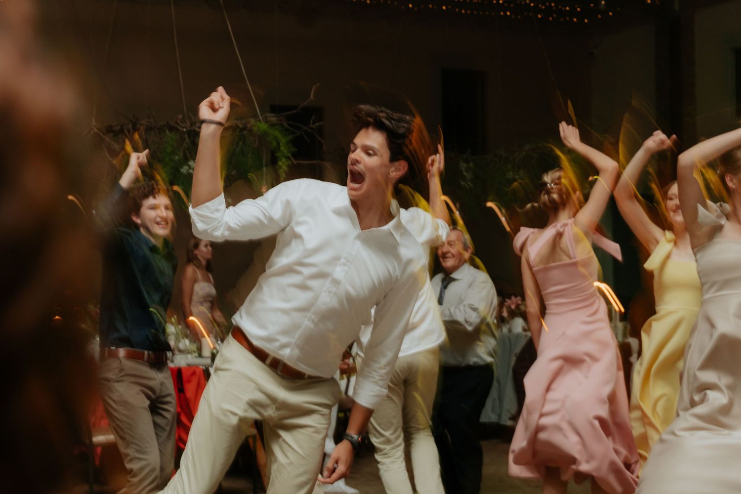 Wedding guests dancing energetically on the dance floor during a reception celebration.