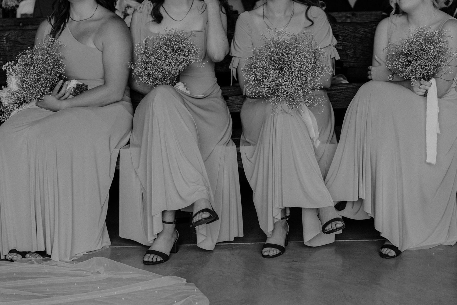 Wedding party members seated in a row wearing coordinated gray dresses.