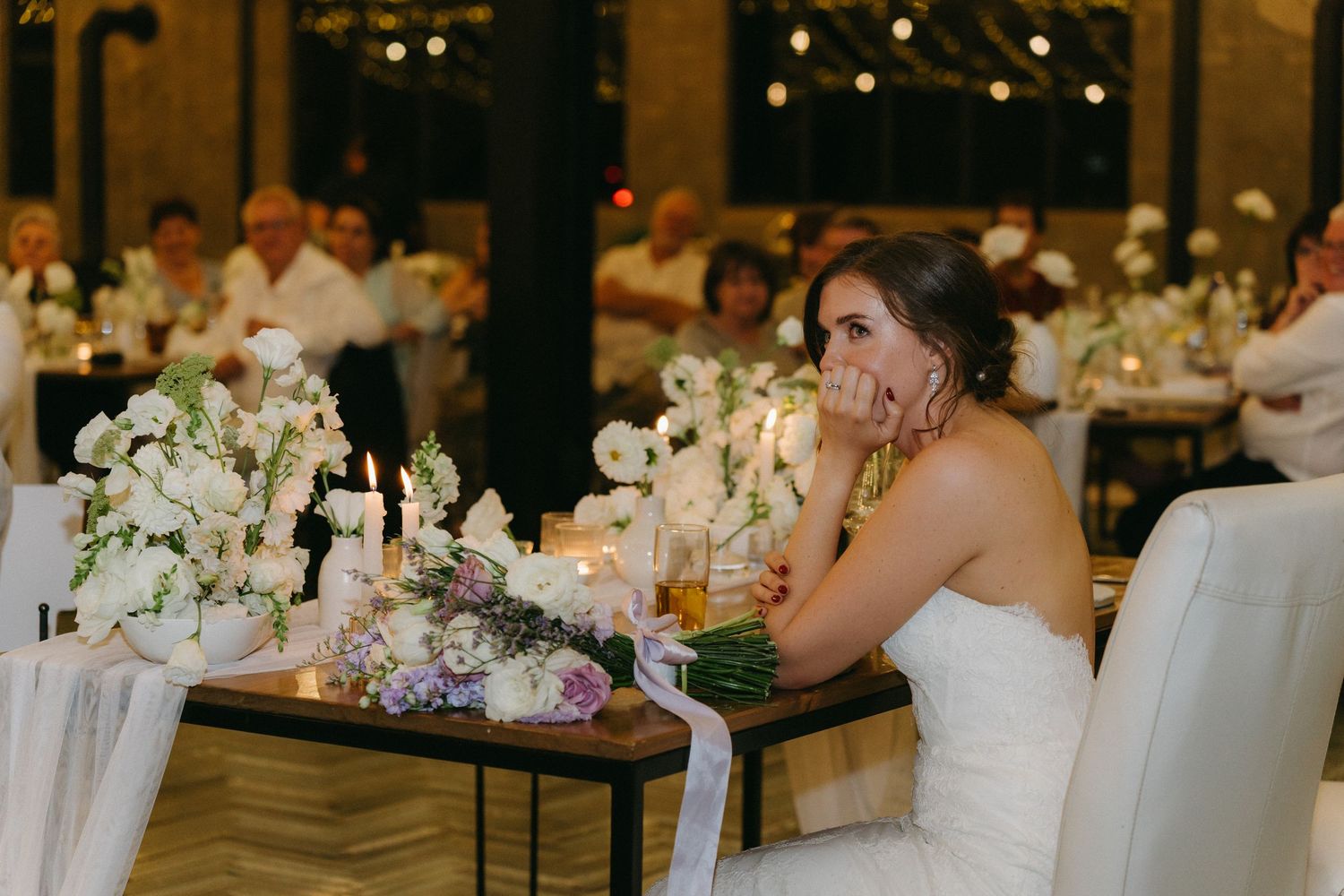 An emotional moment at a wedding reception with white floral centerpieces and elegant table settings in a rustic venue.