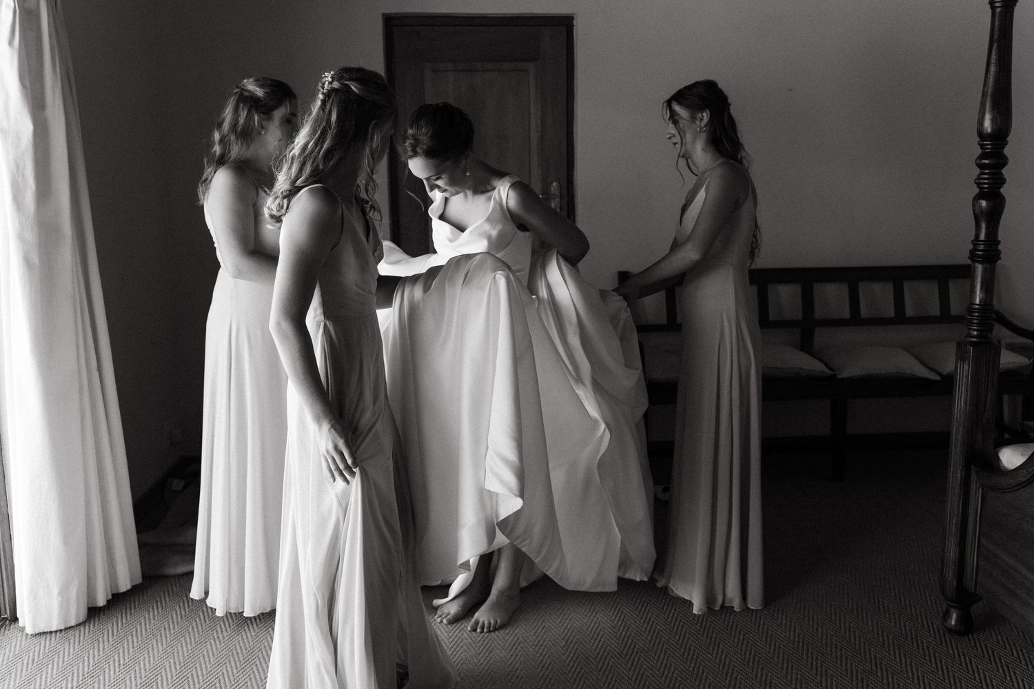 A black and white photo shows a group of people in white dresses preparing in what appears to be a dressing room.