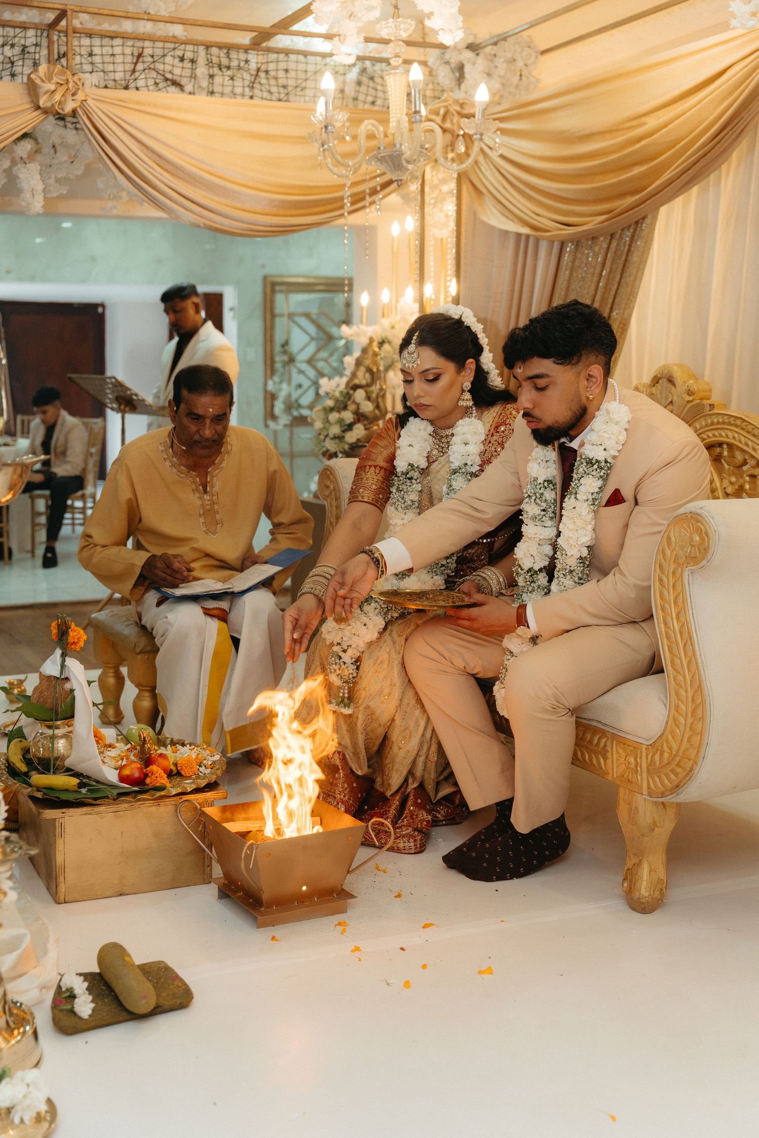 A traditional Indian wedding ceremony ritual with participants performing sacred fire rituals in an ornate venue.