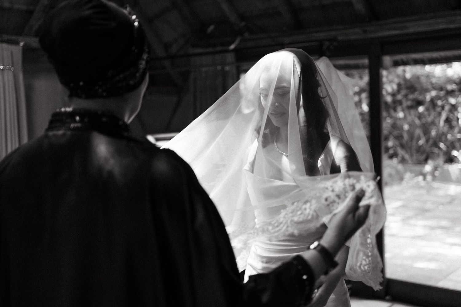 Black and white photo of a bride in a veil being helped by her mom before her wedding ceremony at Oakfield Farm, Johannesburg