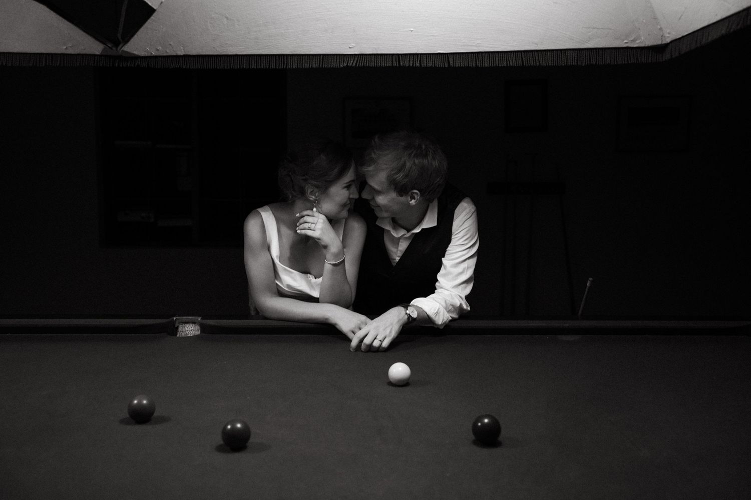 Couple sharing romantic moment leaning over pool table  at Steynshoop Valley Lodge, Hekpoort in black and white photography.