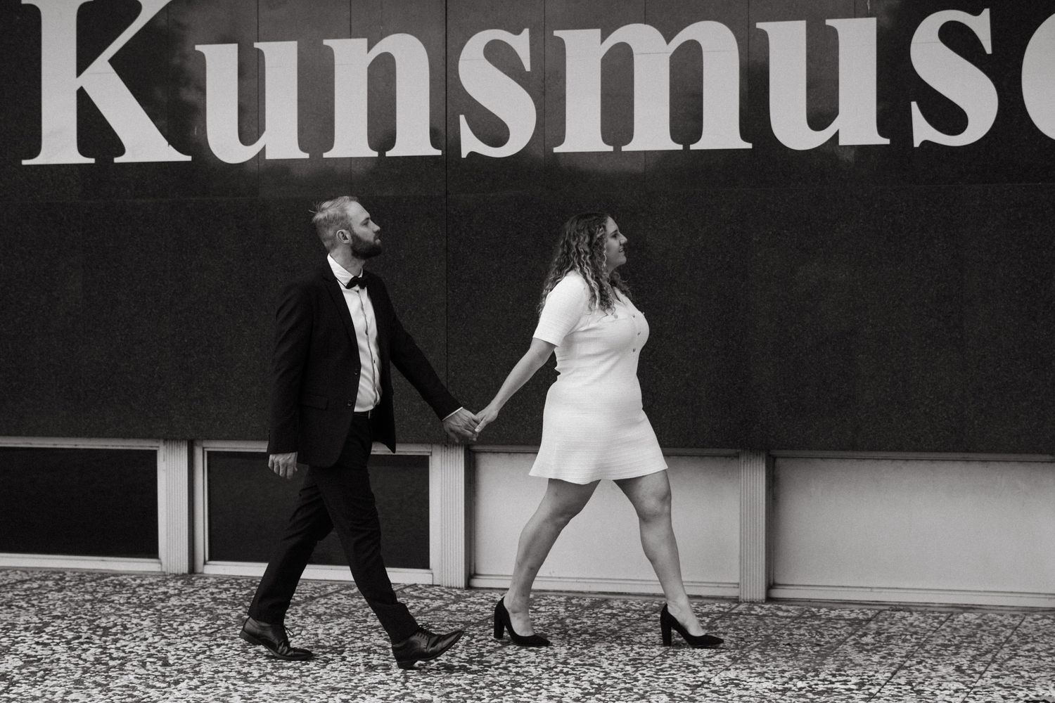 Two people dance outside a Kunstmuseum building in black and white photography.