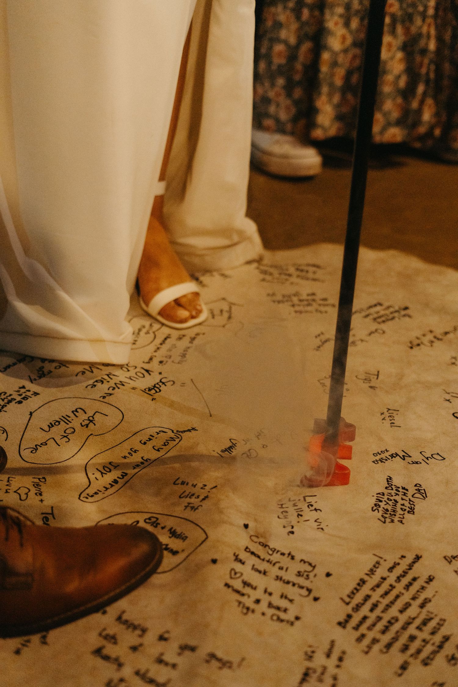 Wedding dress and shoes visible on a floor covered with handwritten messages and signatures.