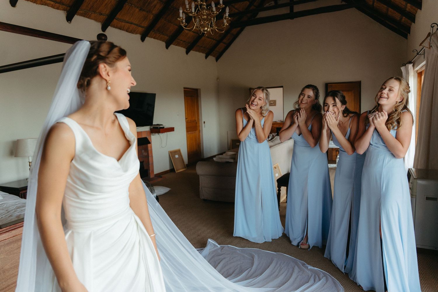 Wedding party members in light blue bridesmaid dresses and white bridal gown gathered in a rustic venue.