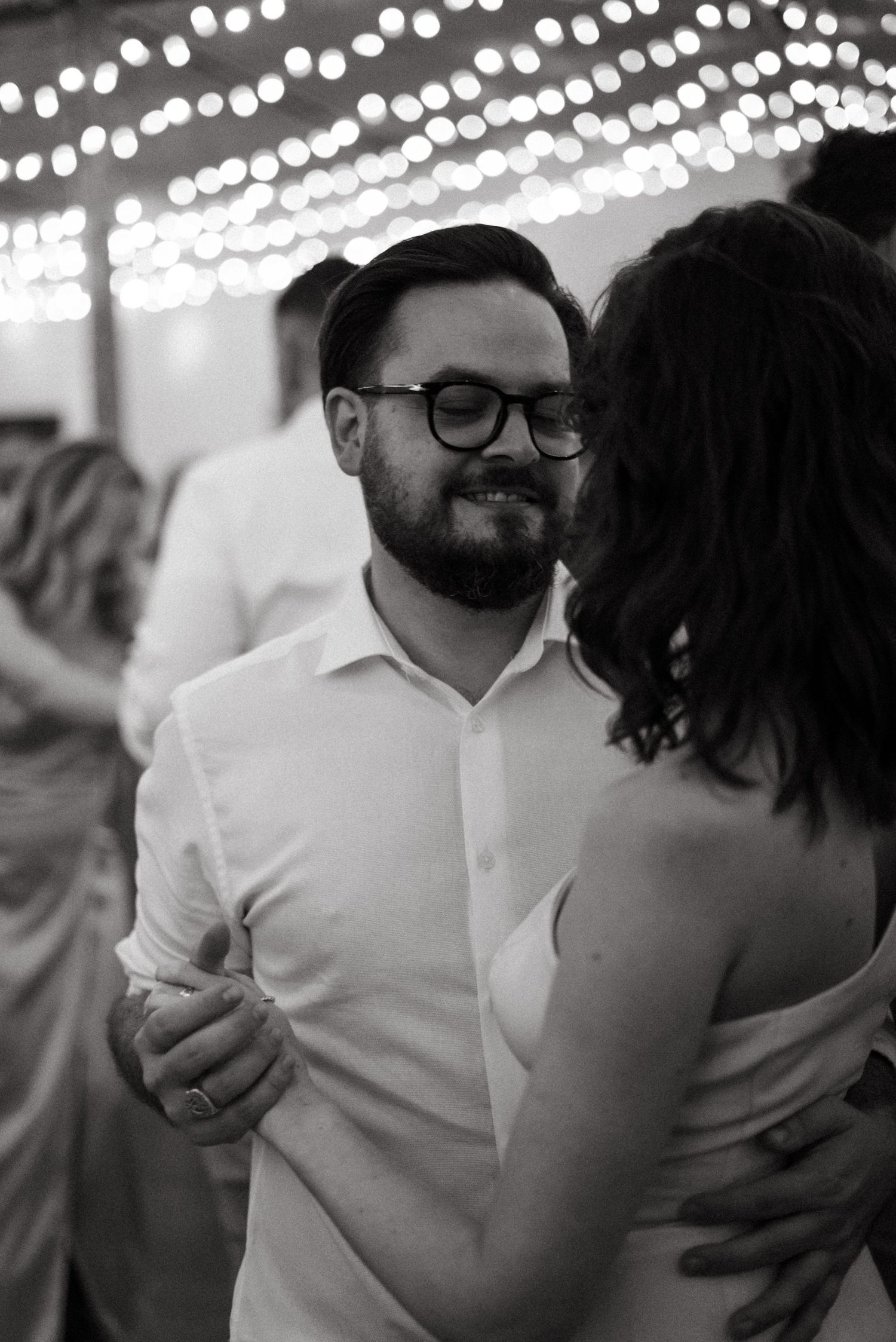 Romantic first dance under twinkling string lights at wedding reception.
