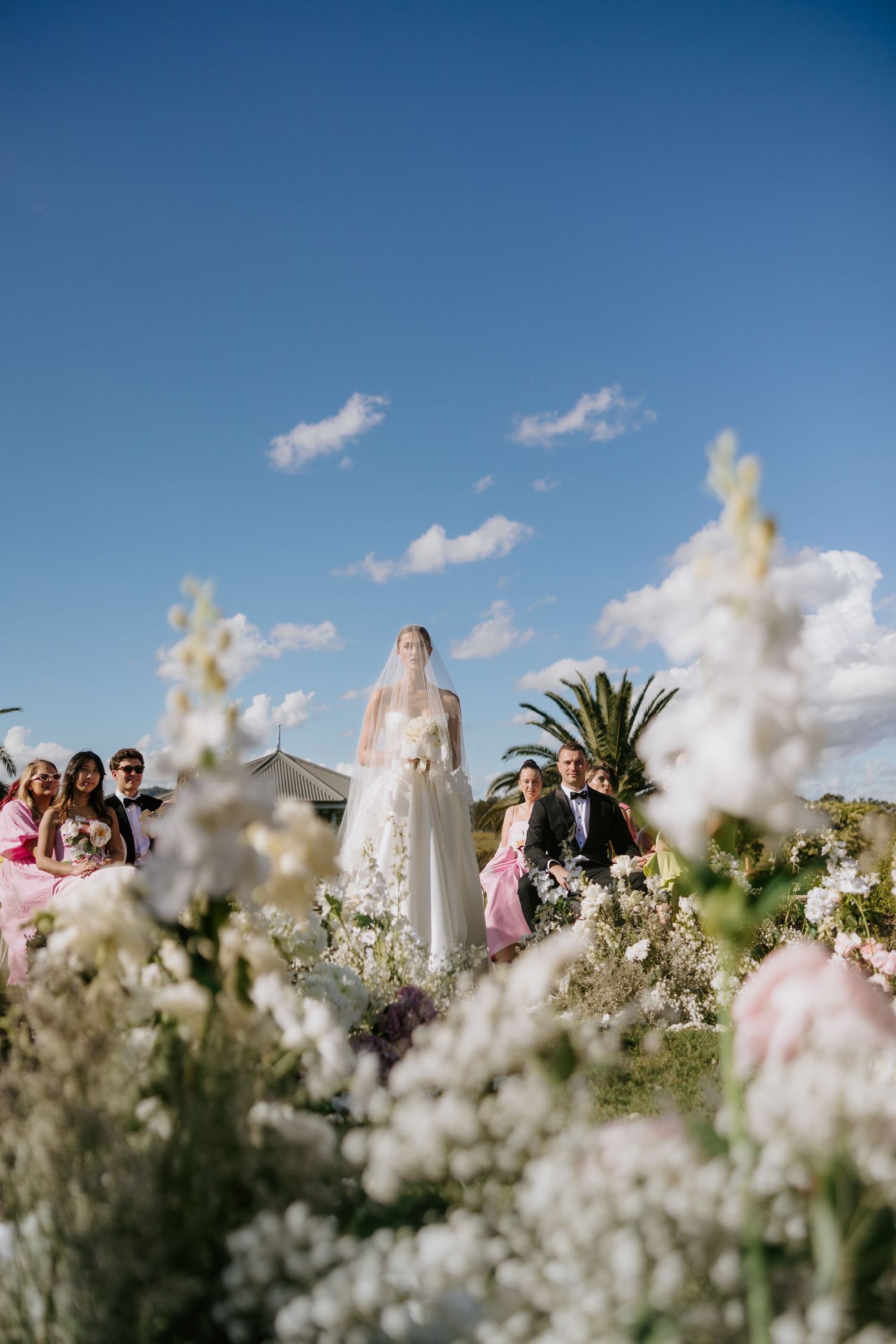 Sydney wedding photography of bride walking down aisle with florals in foreground