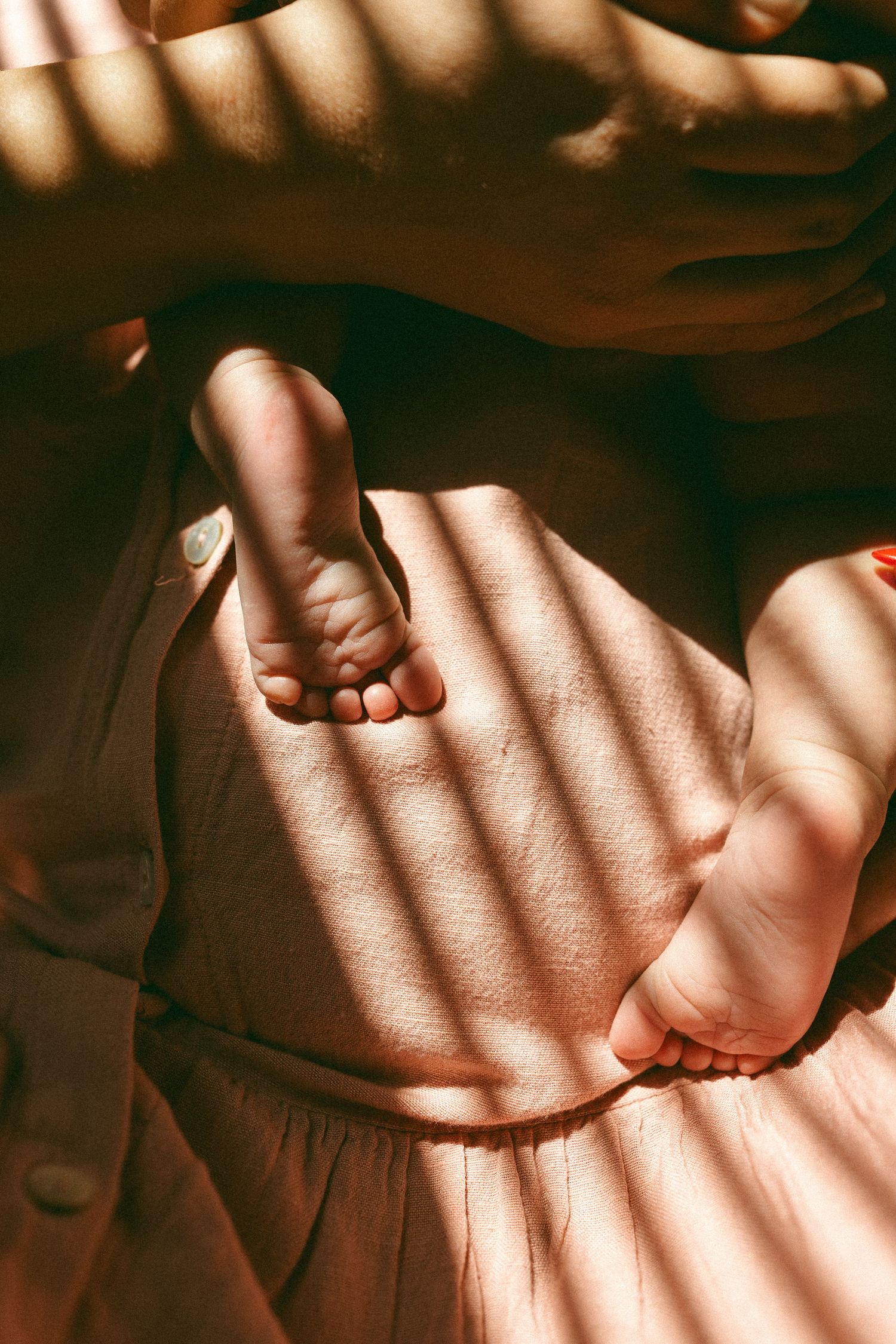 Mother holding her newborn with a close-up of baby's feet during a lifestyle newborn photography session in Mesa, Arizona