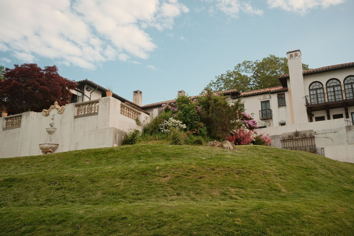 Outdoor architectural scene featuring a building surrounded by greenery and flowers.