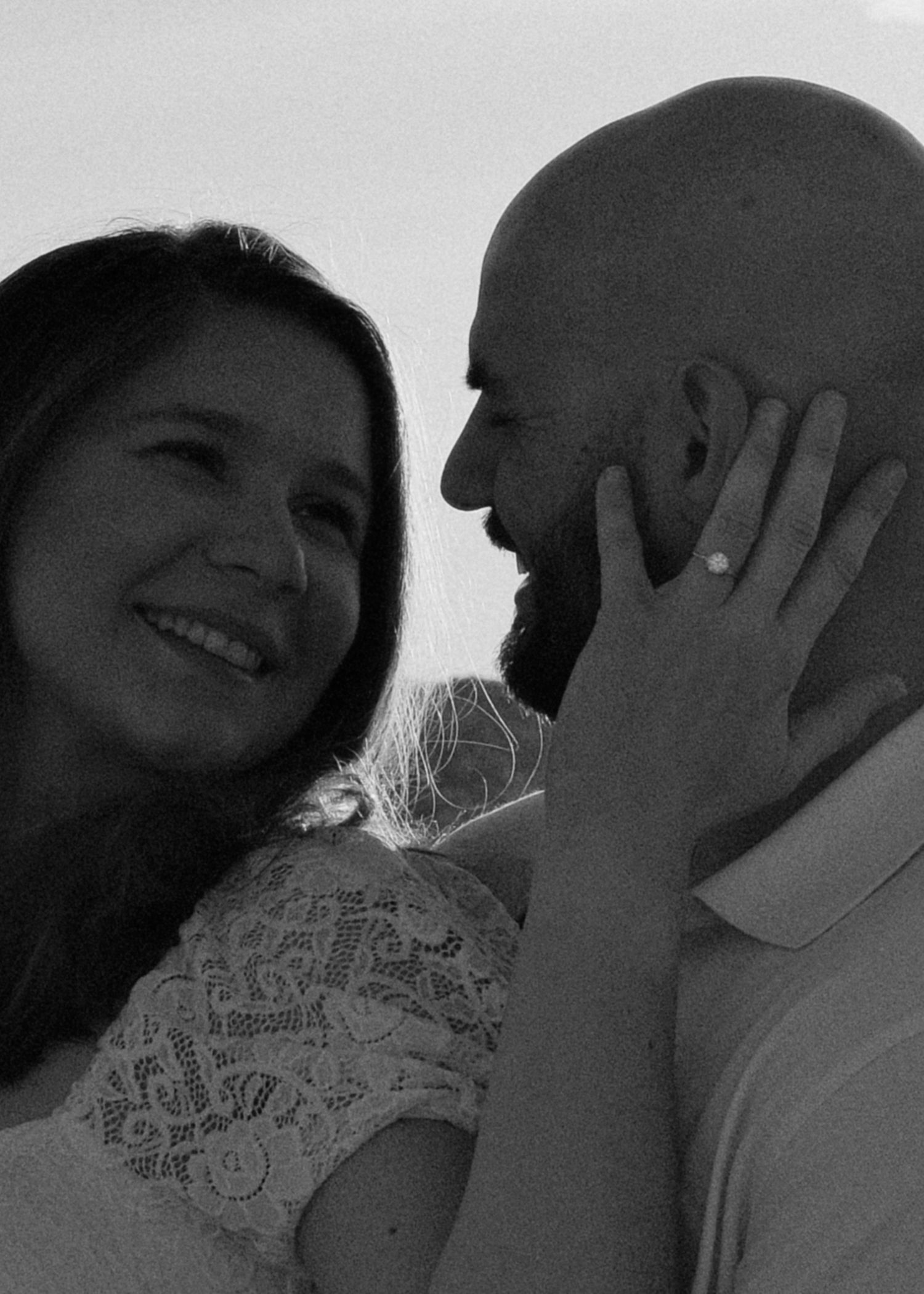 Black and white close-up engagement portrait with film-inspired grain and natural light.