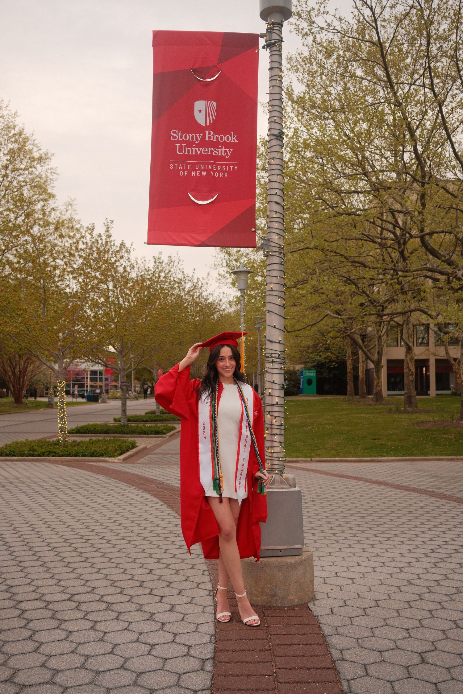 Graduate standing and smiling during an outdoor portrait session on Long Island.