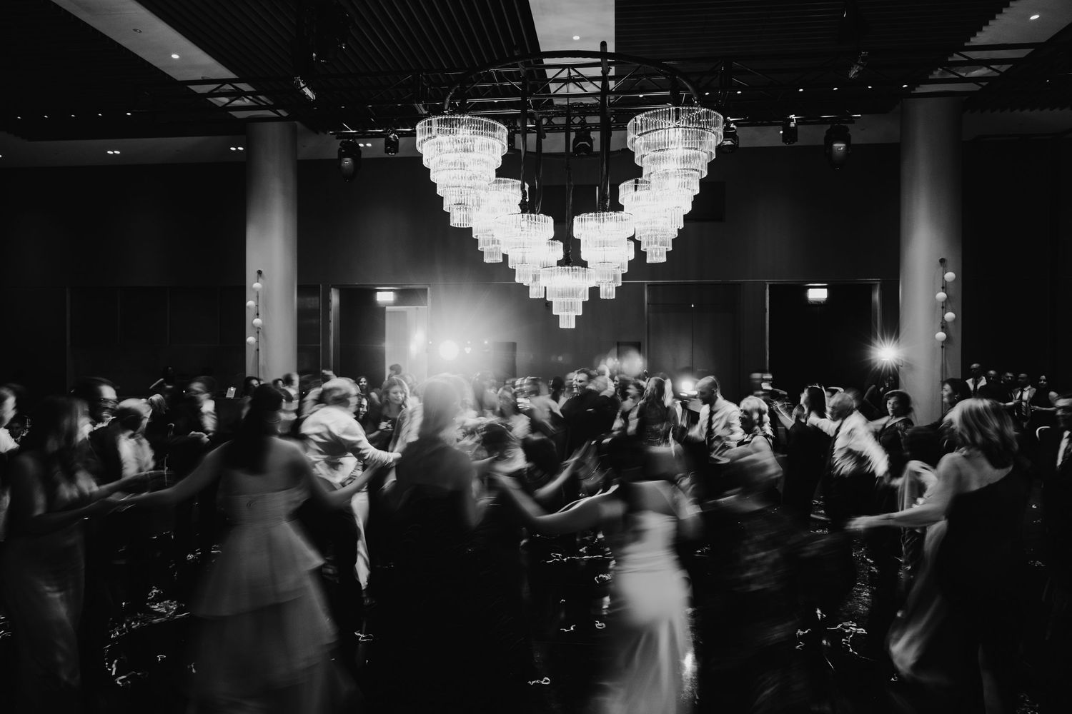 Black and white wedding reception dance floor with elegant chandeliers and guests celebrating in a grand ballroom.