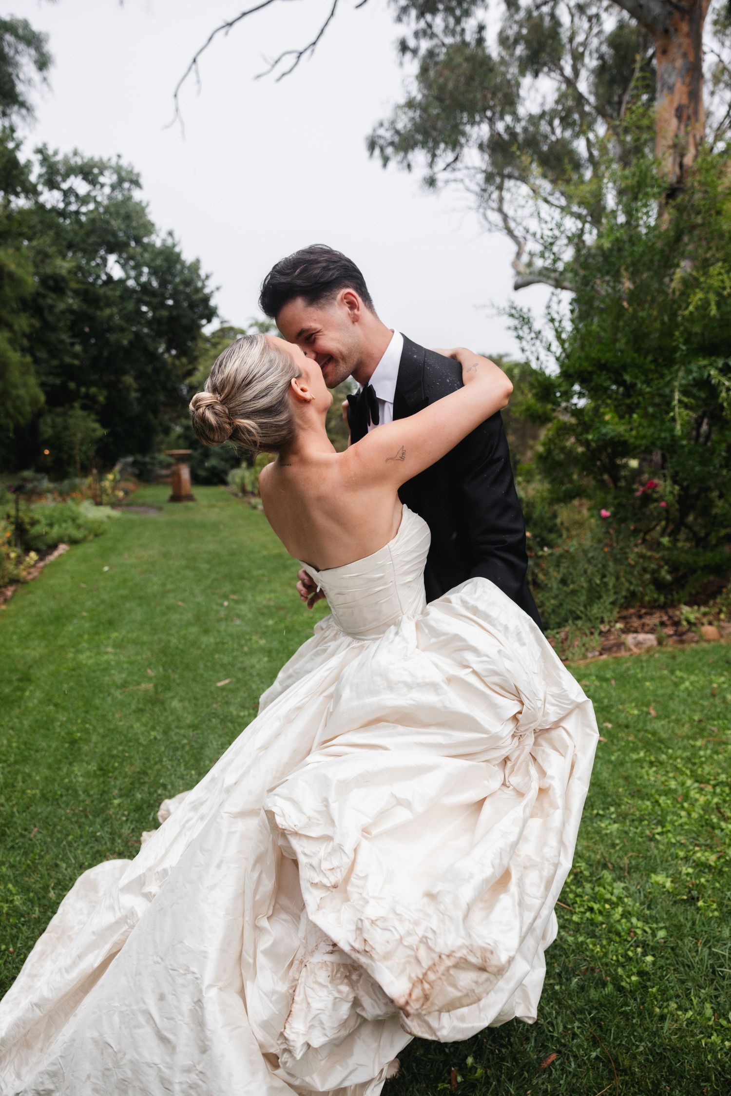 Bride and groom share romantic dance in lush garden, bride wearing strapless ballgown wedding dress.