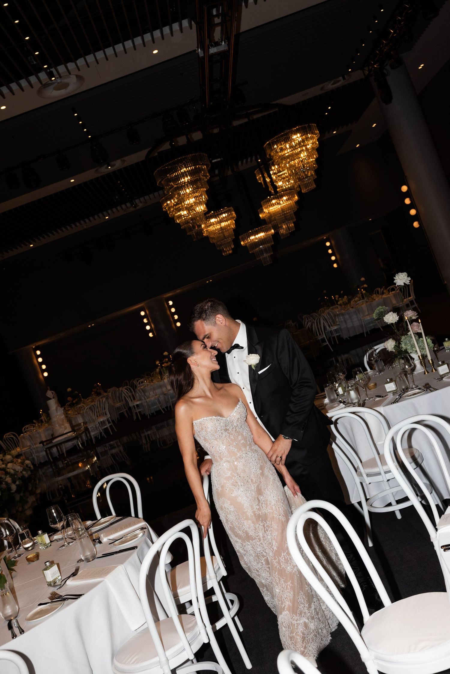 Bride and groom sharing romantic kiss in elegantly decorated wedding reception hall.