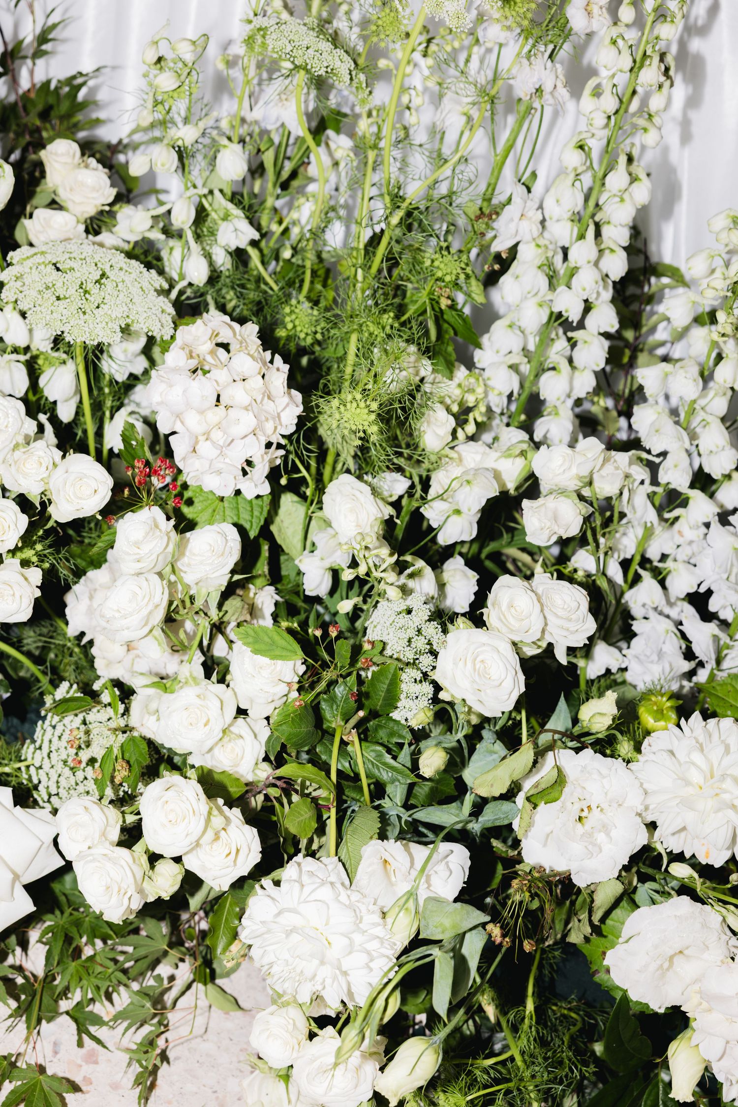 Lush white wedding floral arrangement featuring hydrangeas, roses, and wildflowers with green foliage.