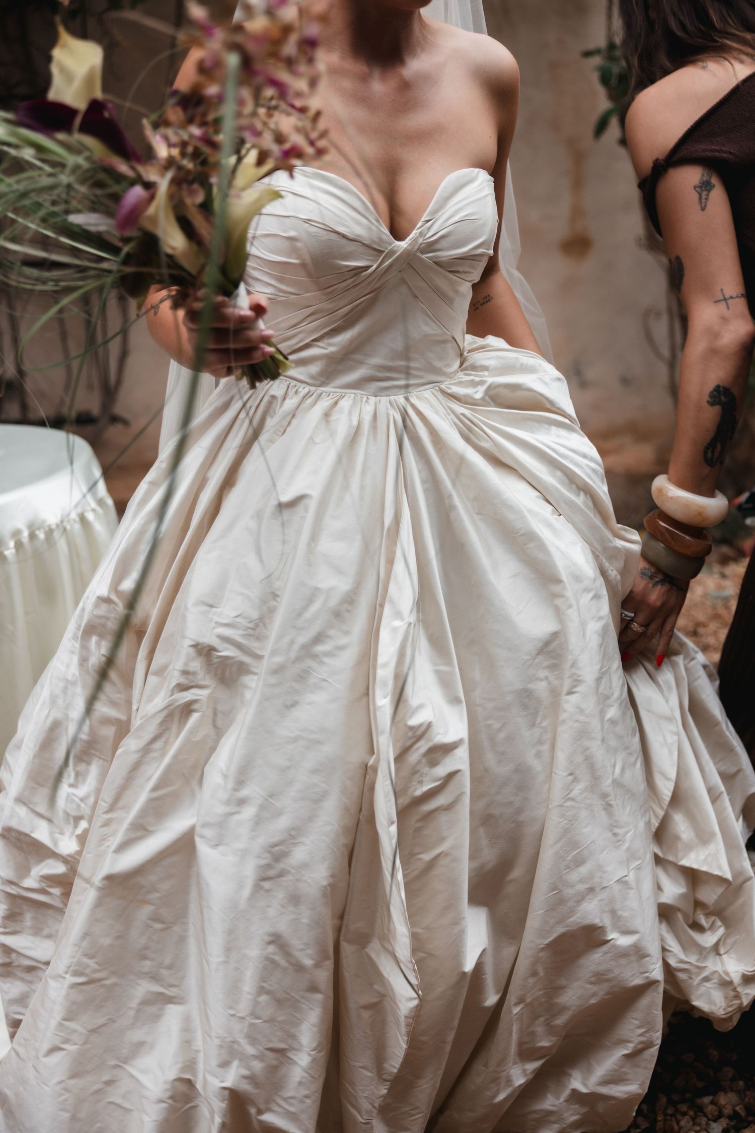 Bride in strapless ivory silk ballgown holding bouquet surrounded by wedding party members.