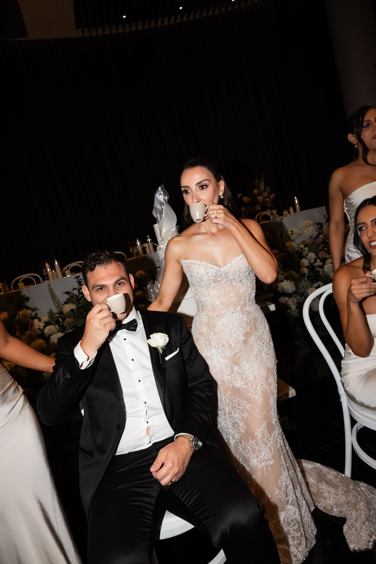 Bride and groom sipping espresso together at wedding reception table.