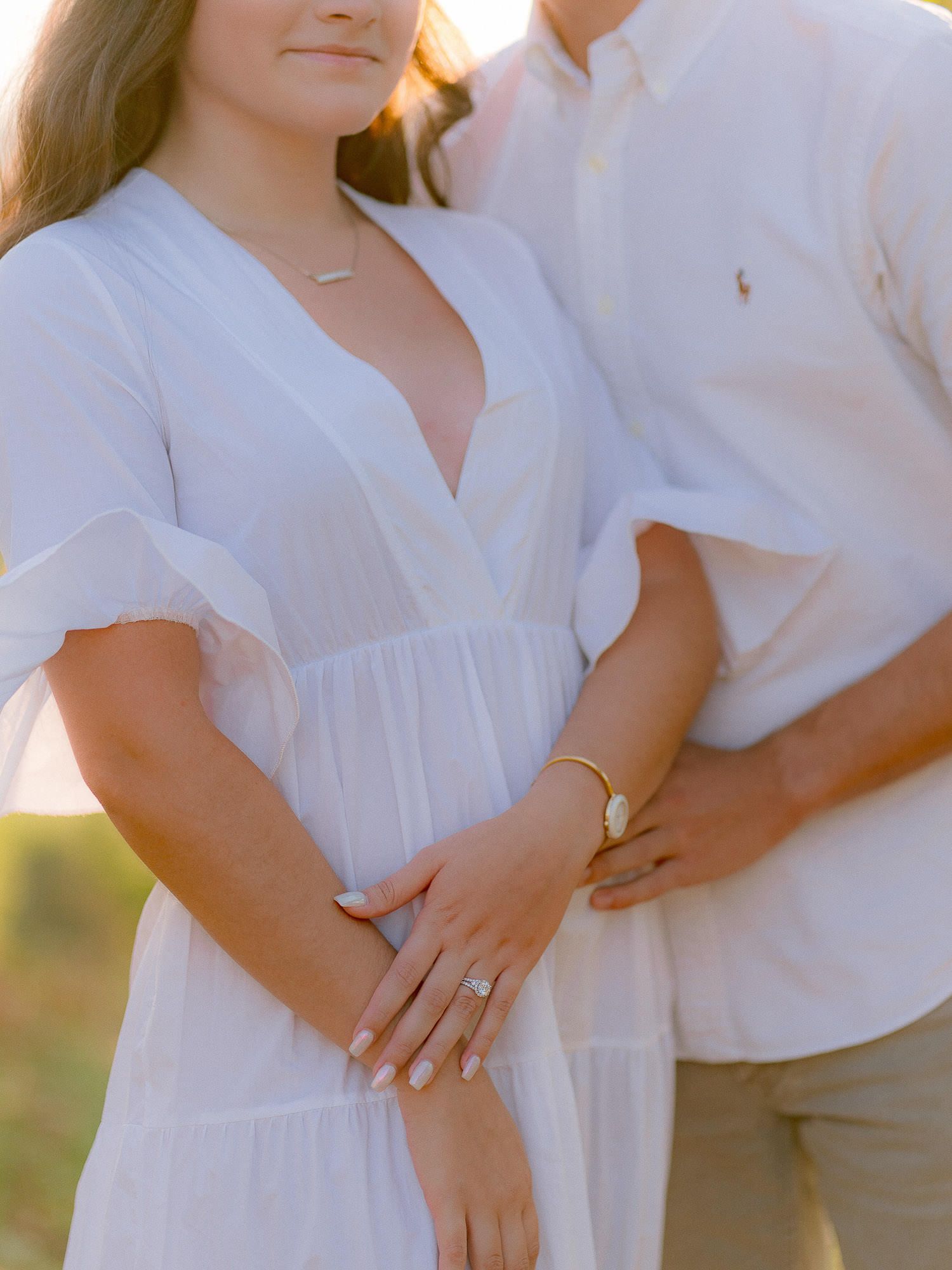 Close-up detail of white summer outfits and engagement ring.