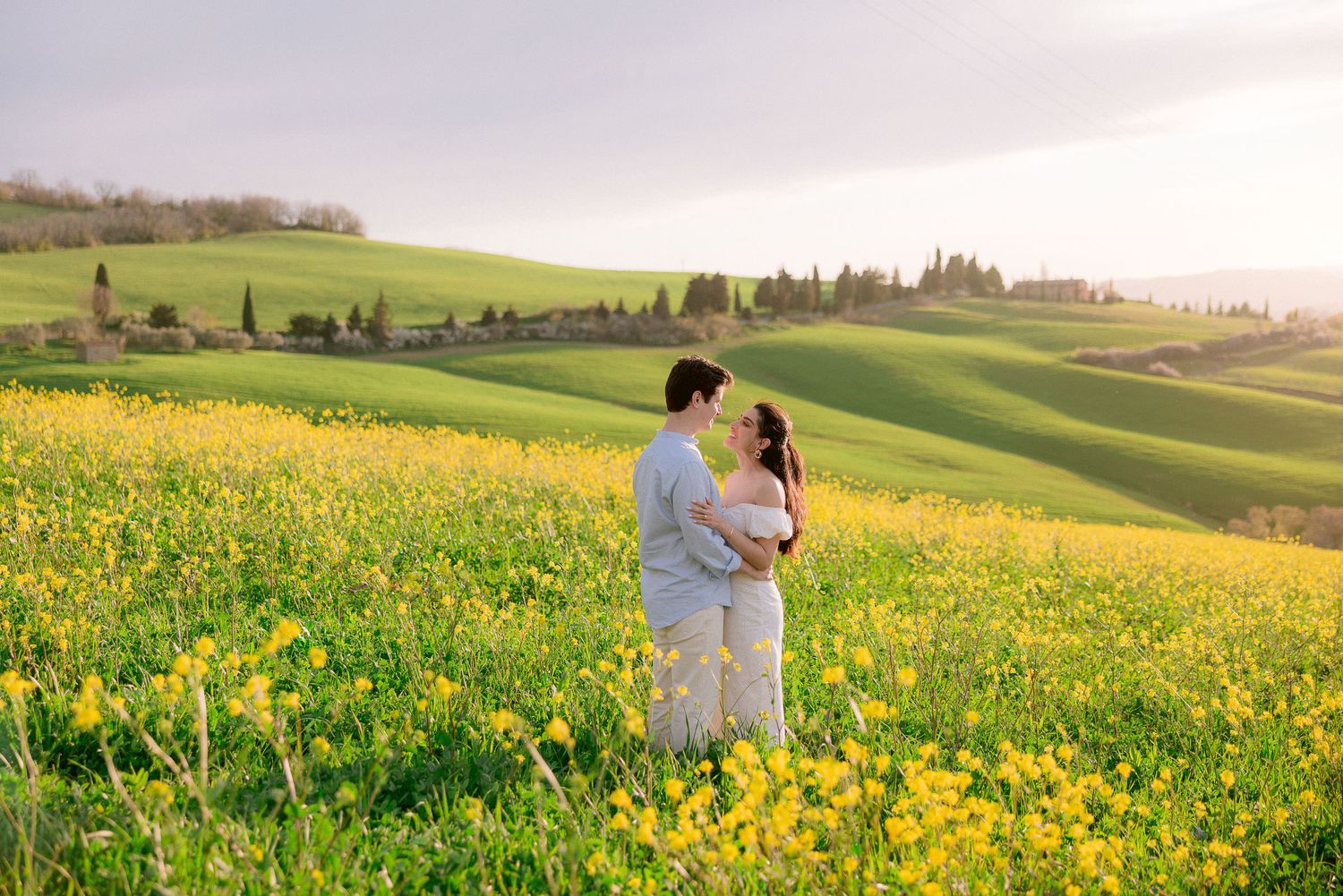 A couple walks through a vibrant yellow wildflower field in the Italian countryside.