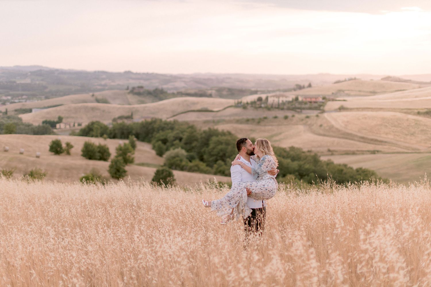 Rolling Tuscan hills stretch into the distance under a warm sunset sky.