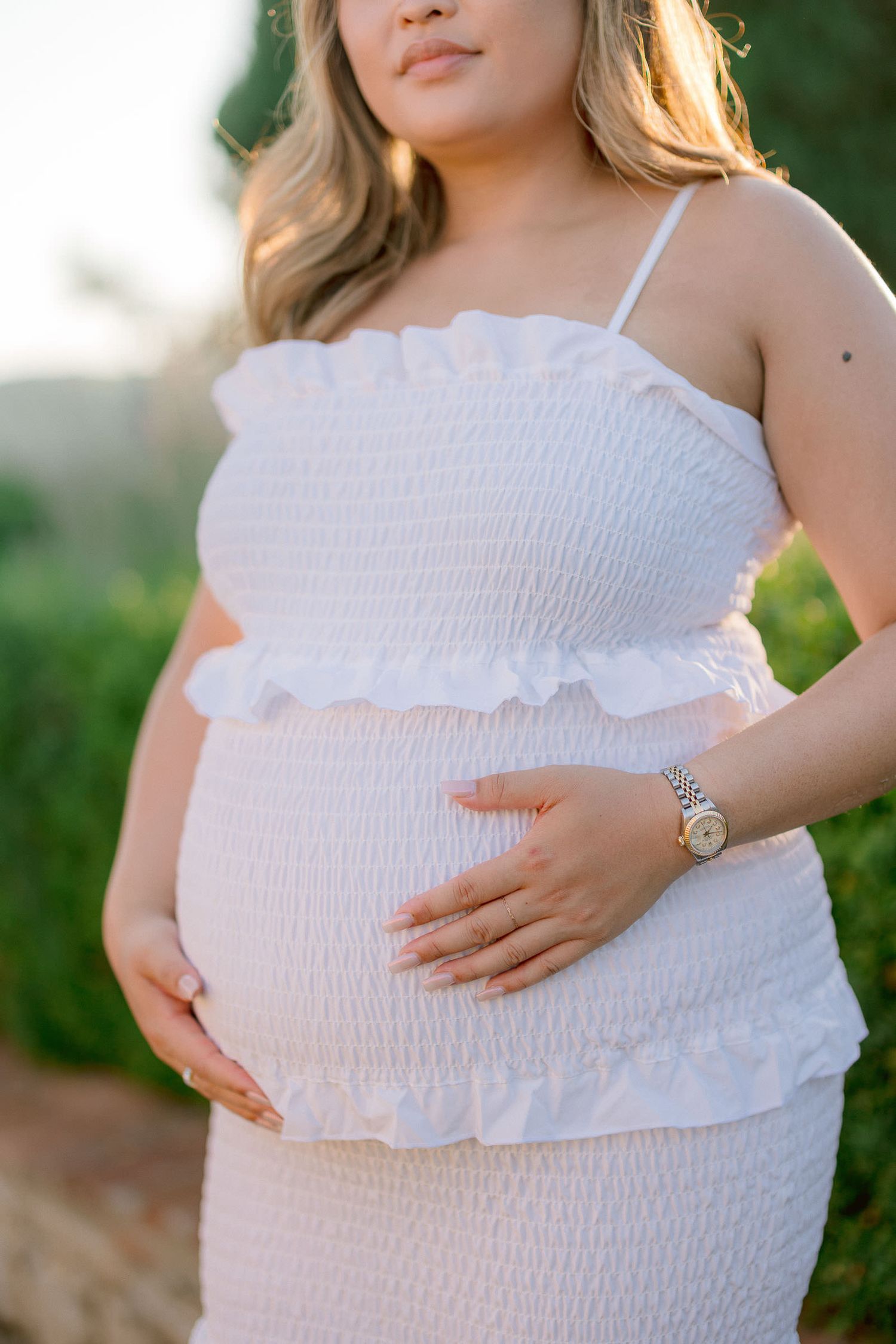 Close-up of a white smocked maternity dress with ruffle details.