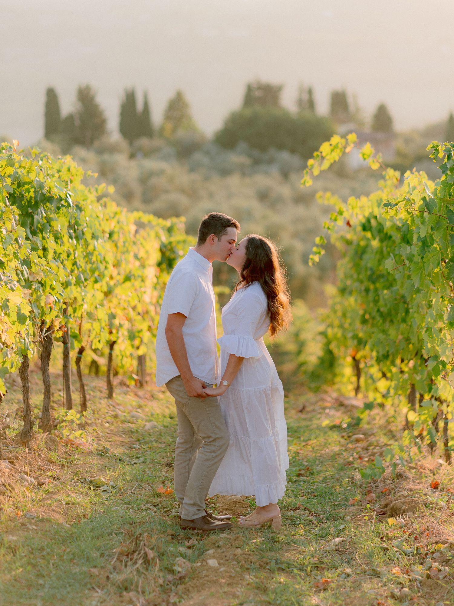 Romantic sunset photoshoot in Italian vineyard with golden light filtering through grapevines.