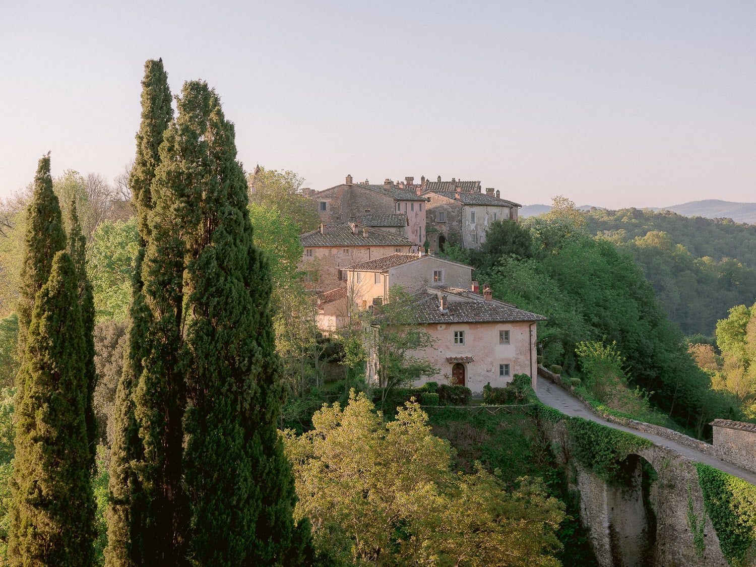 Scenic hillside view of Italian countryside villas and cypress trees at dusk.