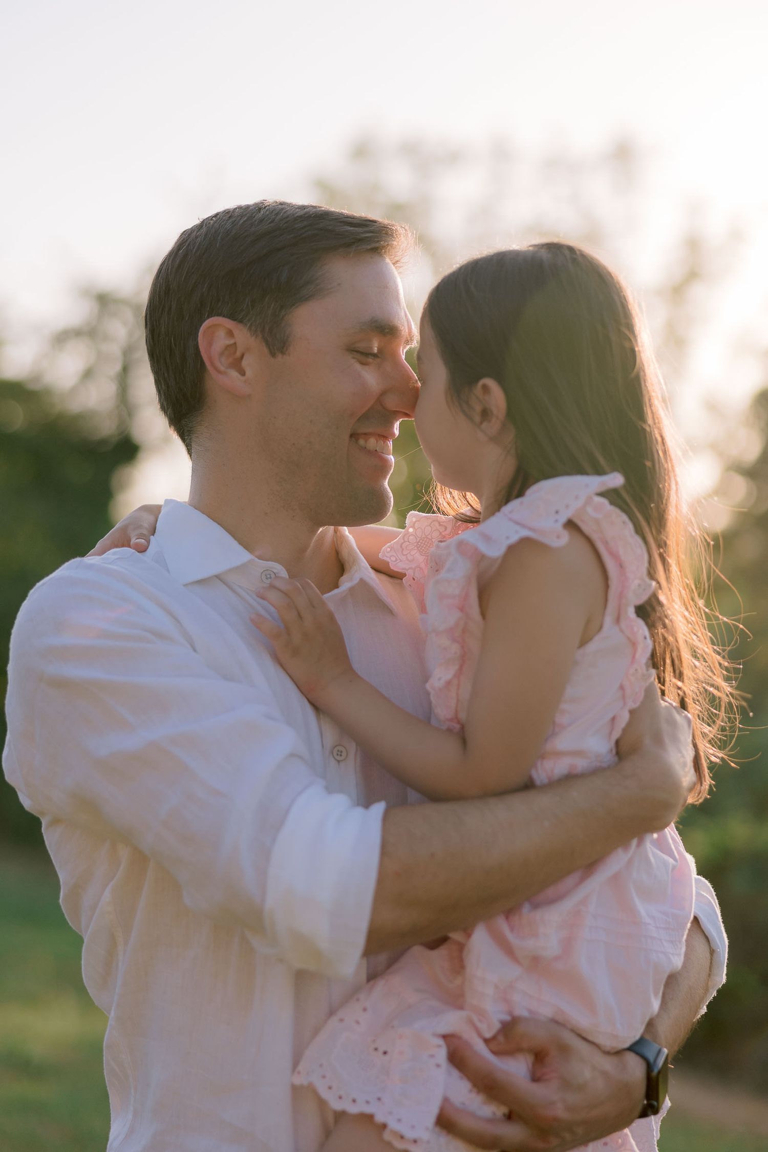 Loving family moment with parent and child embracing in golden sunset light.