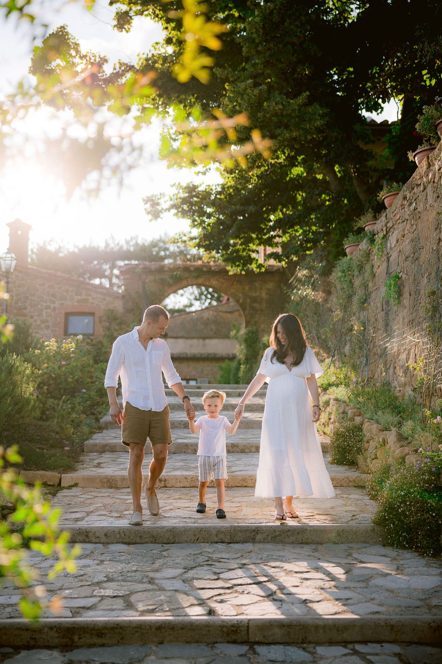 Family plays together on stone pathways during golden hour in a garden setting.