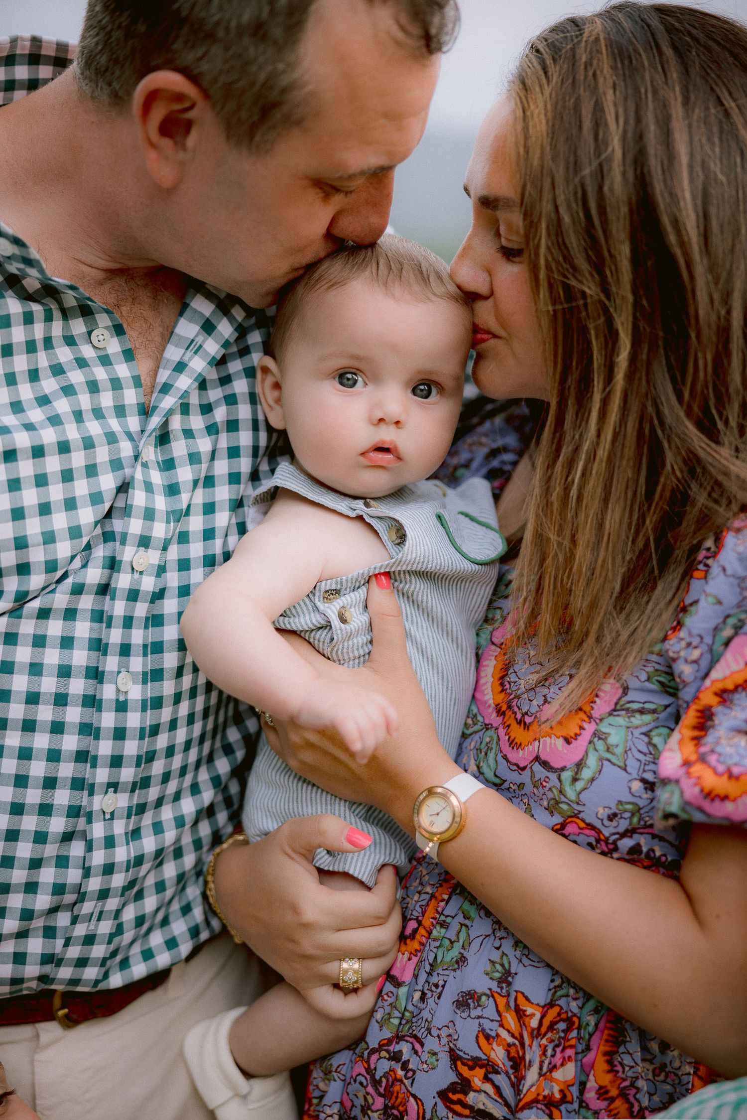 Intimate family portrait series showing tender moments between parents and baby in coordinated green and floral outfits.