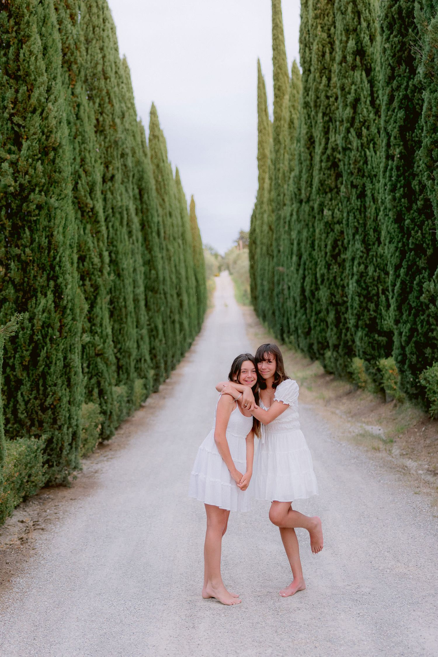 Playful moments captured along a cypress-lined path in Tuscany.