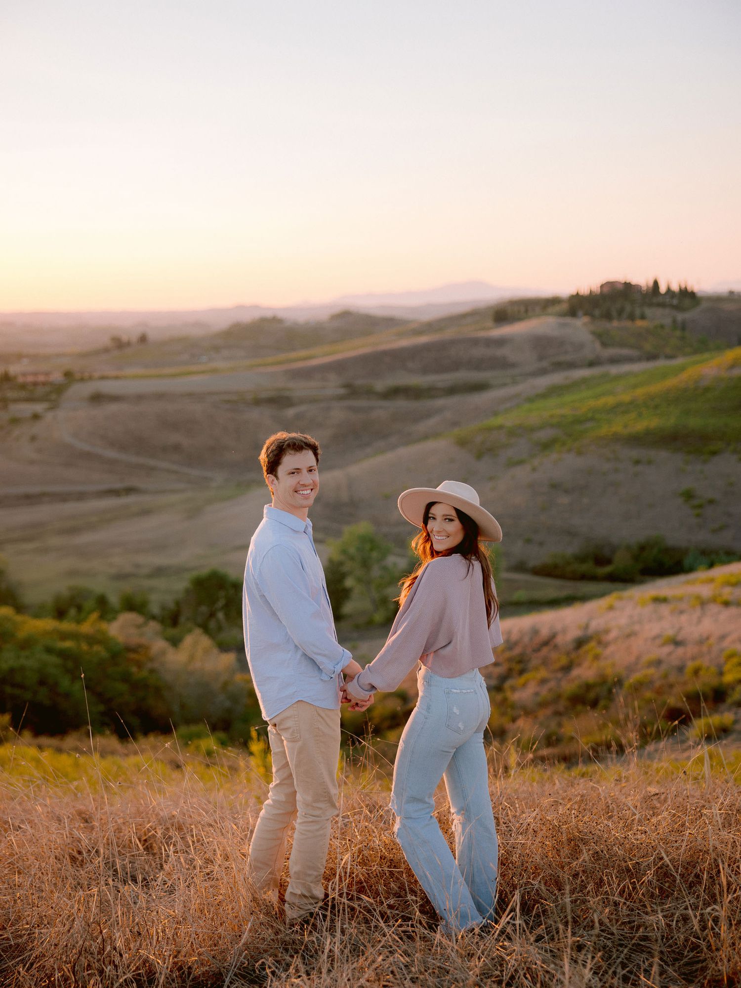 Rolling hills of Tuscany at sunset with golden light illuminating the pastoral landscape.