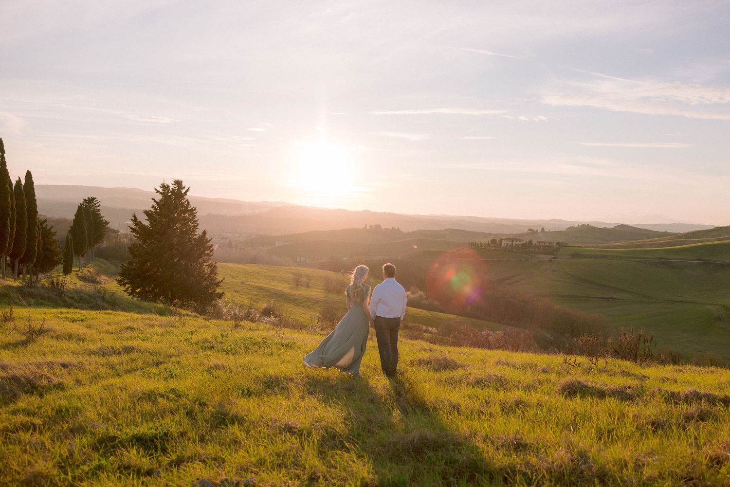 Silhouettes of people walking through a golden field at sunset.