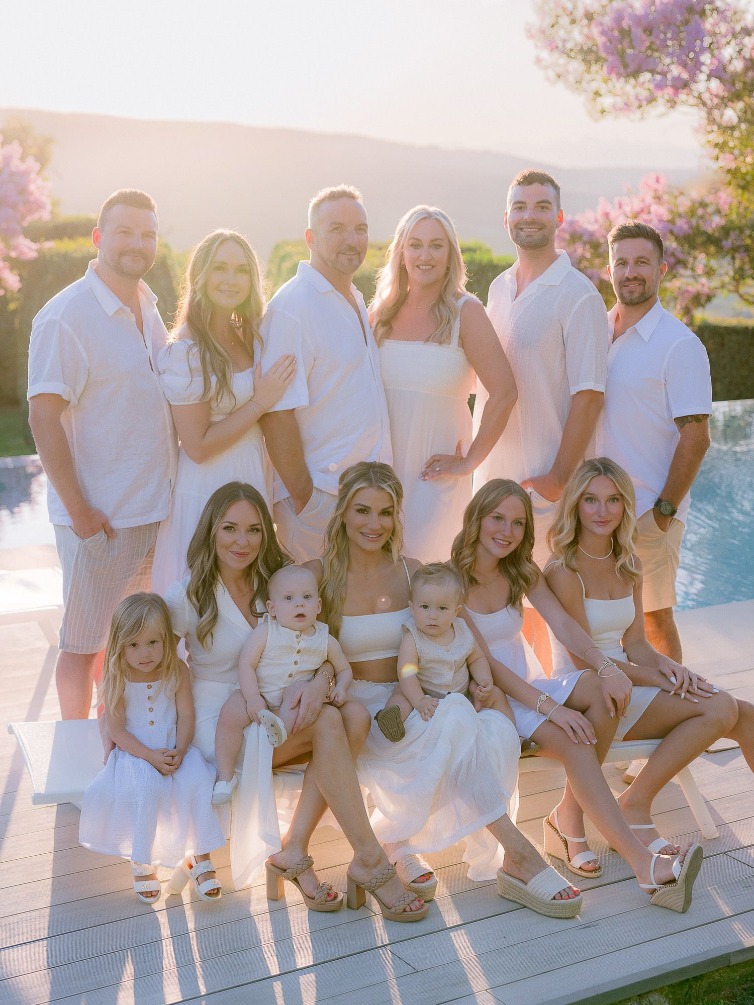 Family gathering photo by the pool with everyone dressed in white.