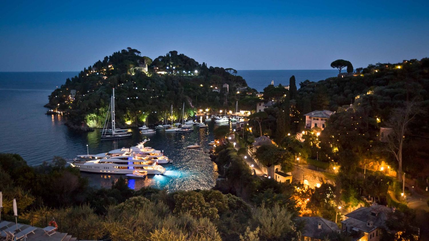 Night panorama of an Italian coastal town illuminated against the dark Mediterranean Sea.