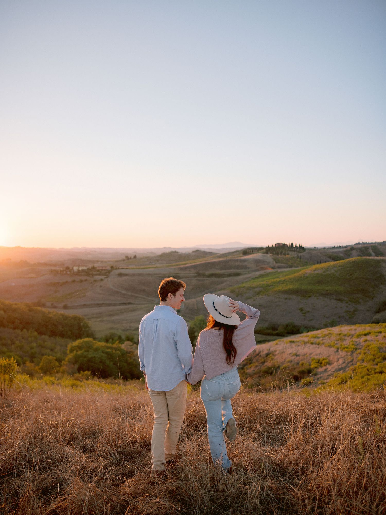 A couple enjoys the golden sunset over rolling Tuscan hills.
