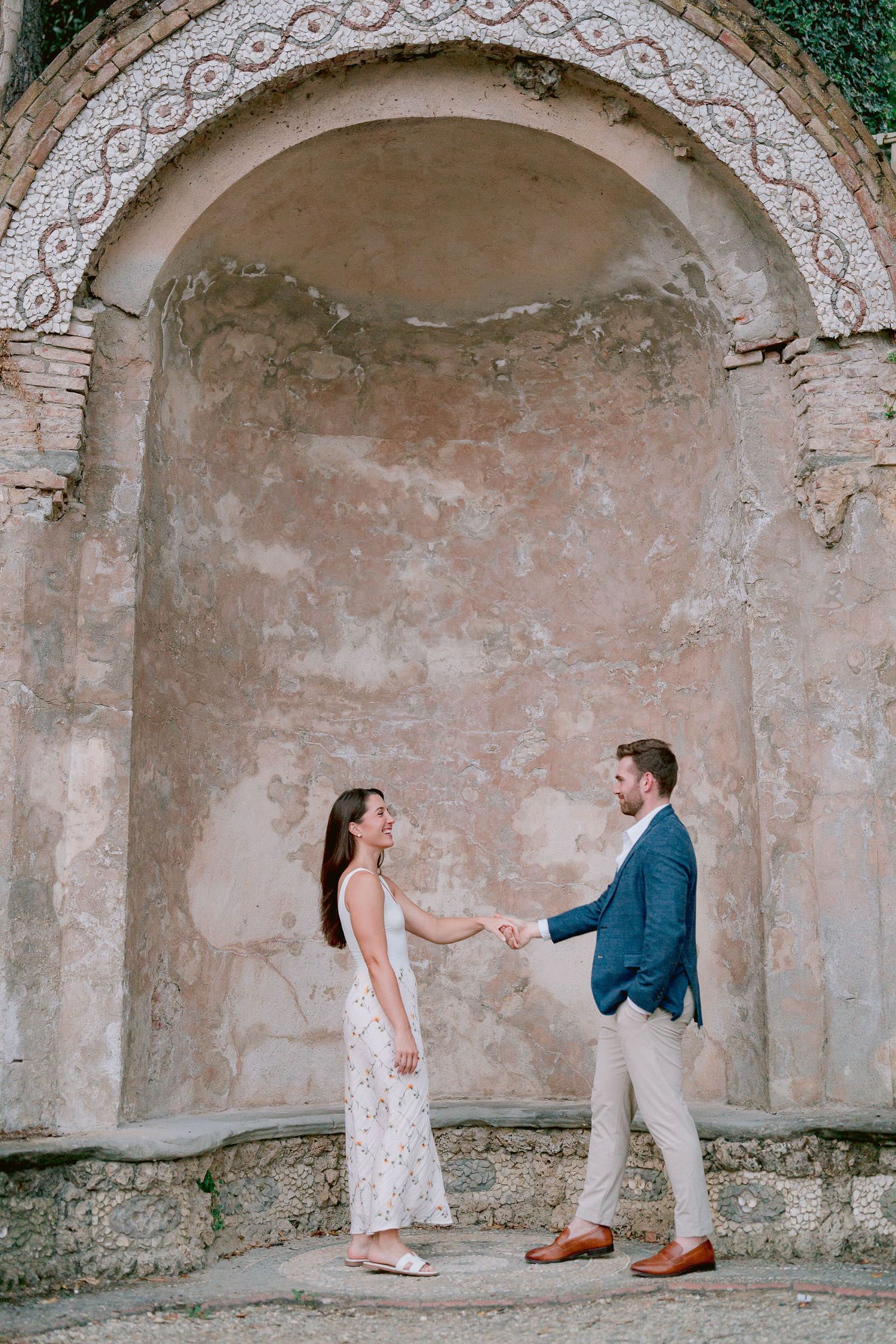 A couple stands in an ornate stone alcove with decorative architectural details.