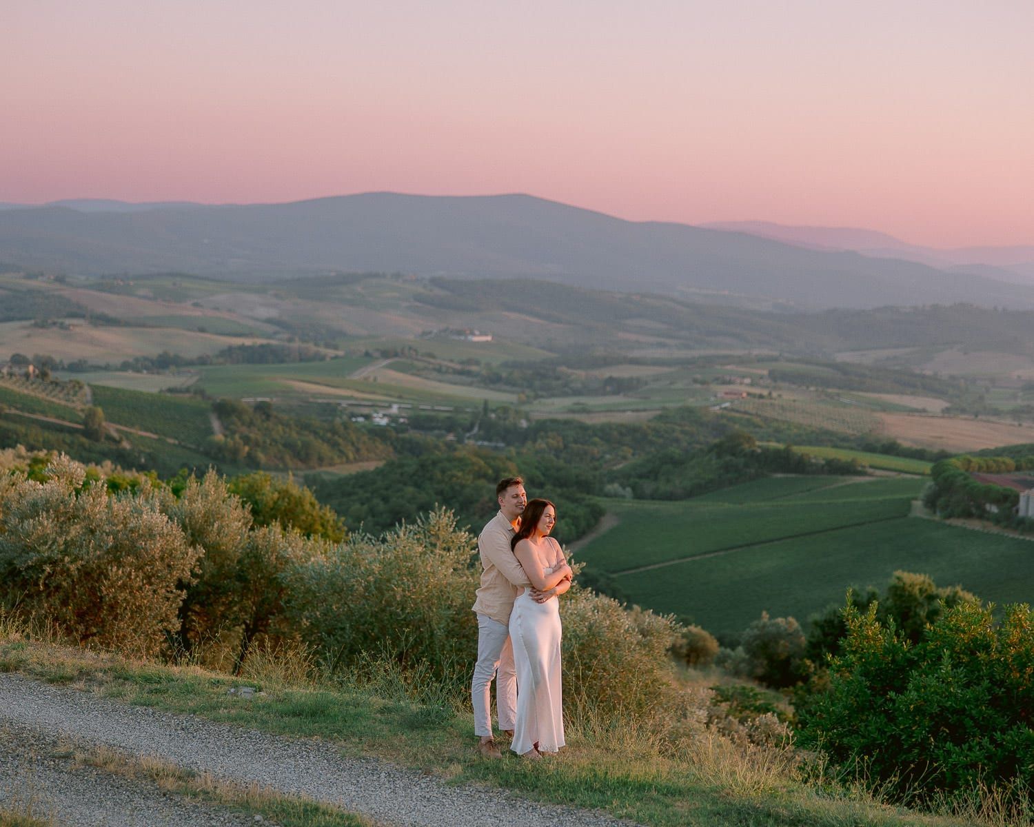 Rolling hills of Tuscany at sunset with cypress trees dotting the pastoral landscape.
