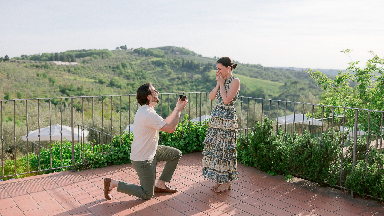 Proposal moment on a terrace overlooking Italian countryside.