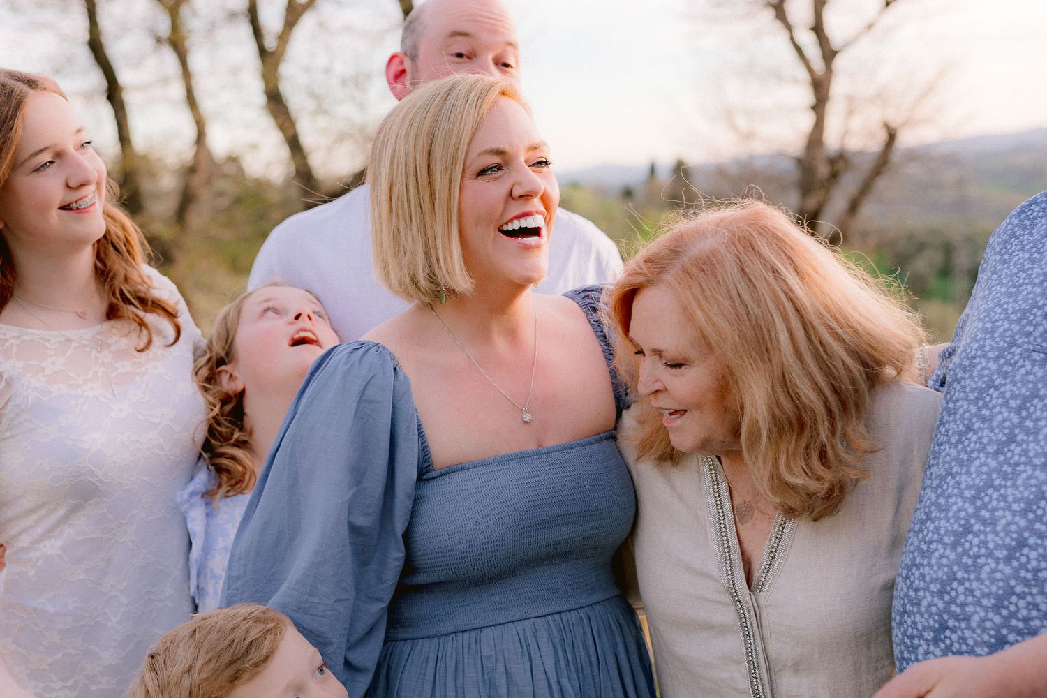 Candid laughing moment between family members in blue and floral dresses.