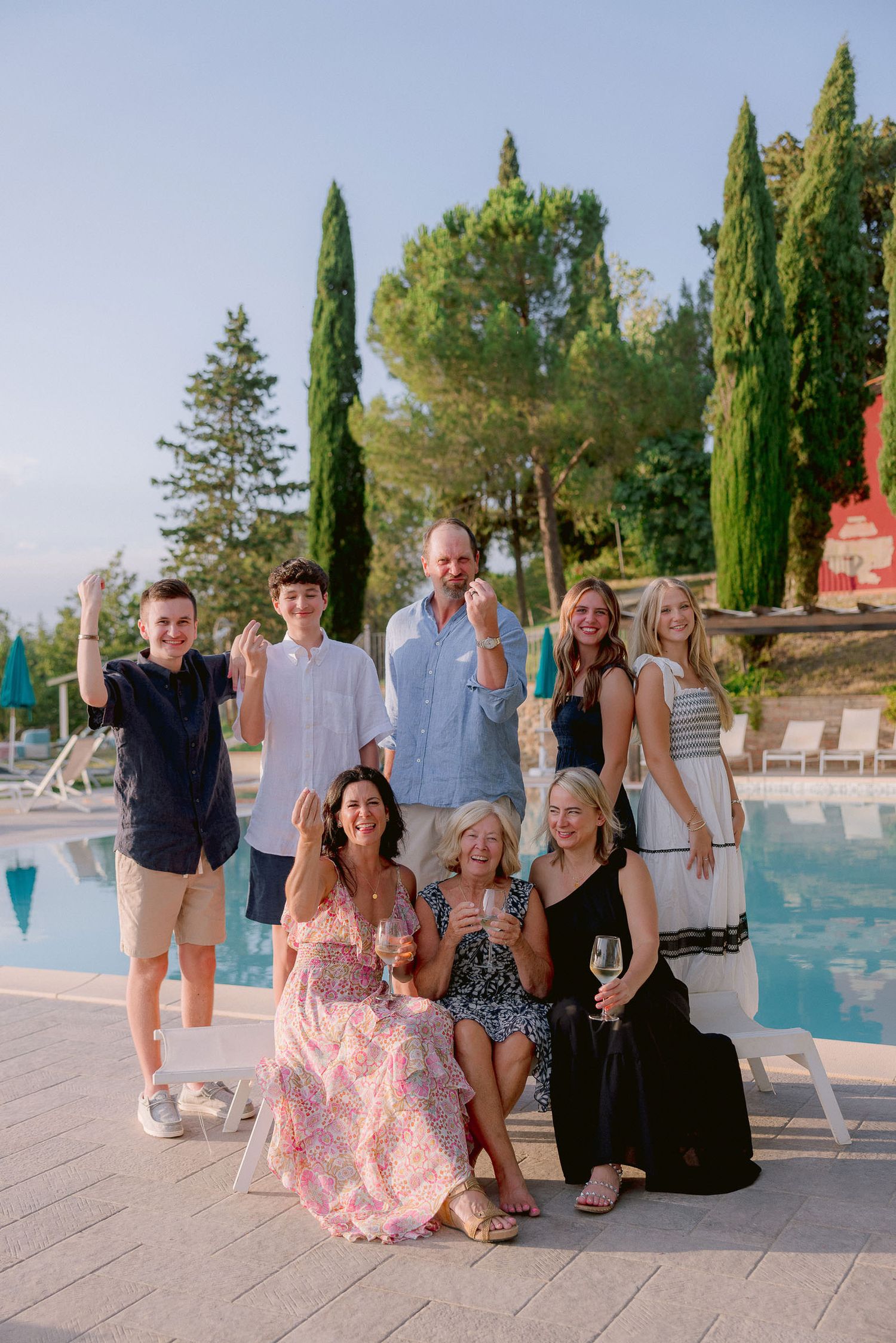 Group of friends gathered by a swimming pool at a Tuscan villa.