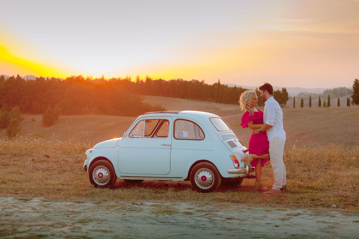 Classic vintage white Fiat car parked in countryside during sunset.