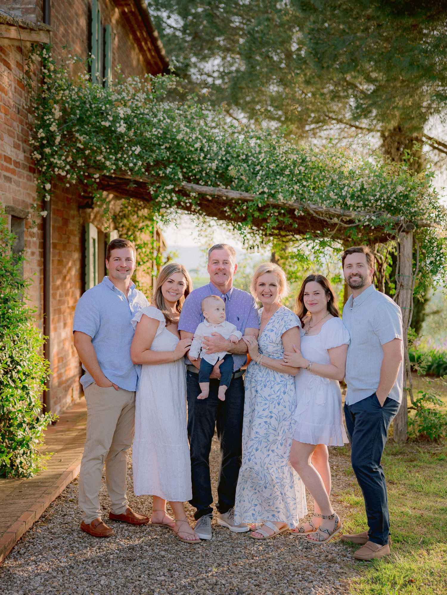 Extended family gathering outdoors in coordinated outfits near brick building.