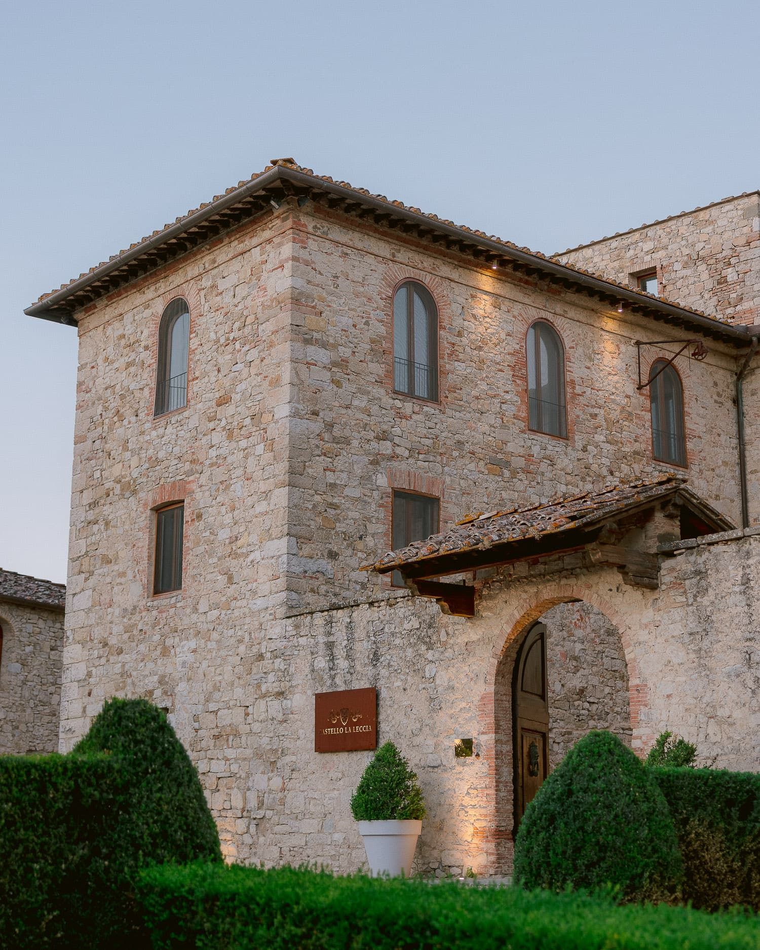 Historic stone villa with traditional Tuscan architecture against clear blue sky.