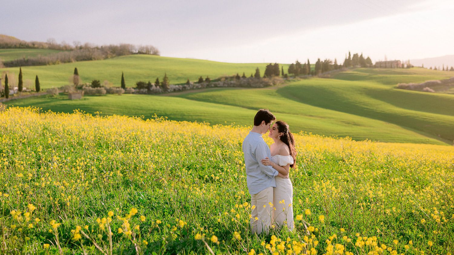 Romantic scene in a wildflower meadow with rolling green Tuscan hills in the background.