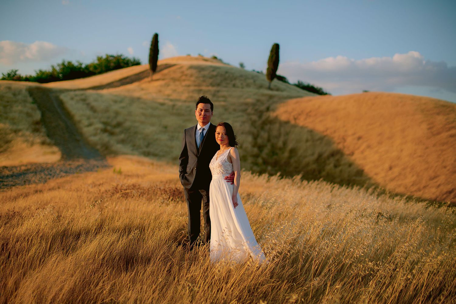 Golden hour engagement photoshoot in rolling Tuscan hills with cypress trees.