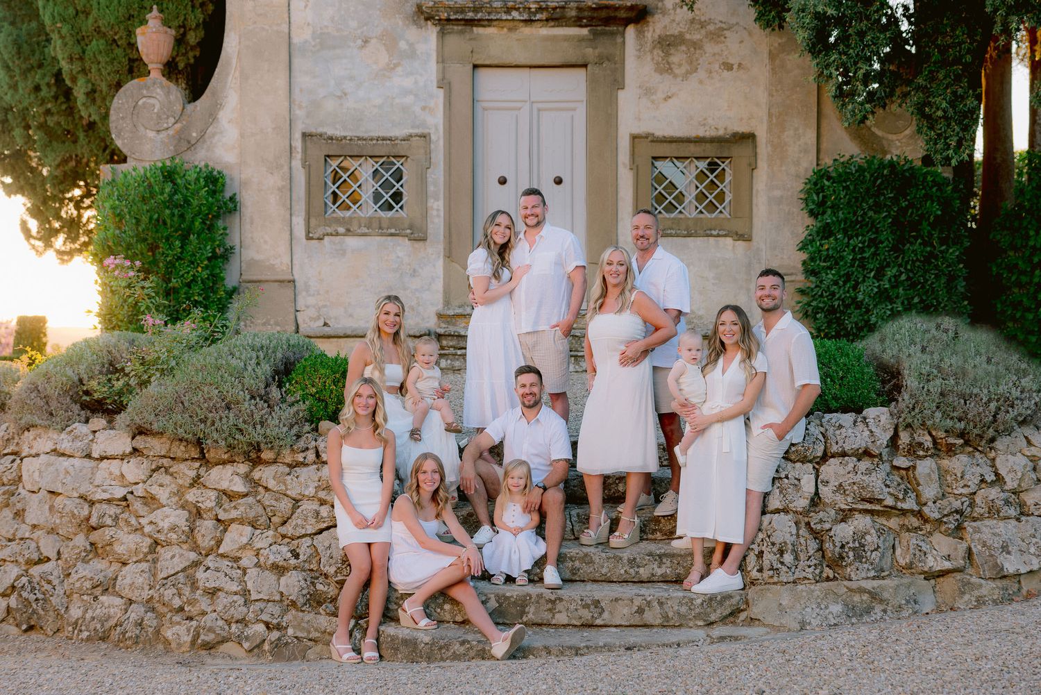 Family photo session on rustic stone steps of a Mediterranean villa at sunset.