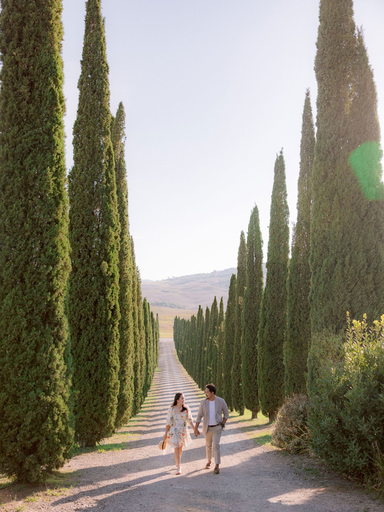 A cypress tree-lined path in the Italian countryside creates a stunning natural archway at sunset.